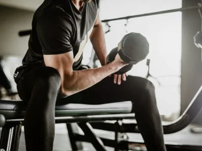 un hombre sentado haciendo un ejercicio para los biceps en un gimnasio