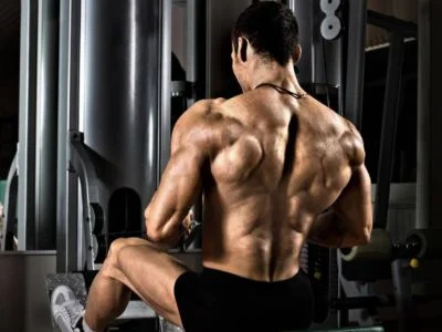 un hombre sentado de espalda a la camara con el torso densudo haciendo un ejercicio para los dorsales